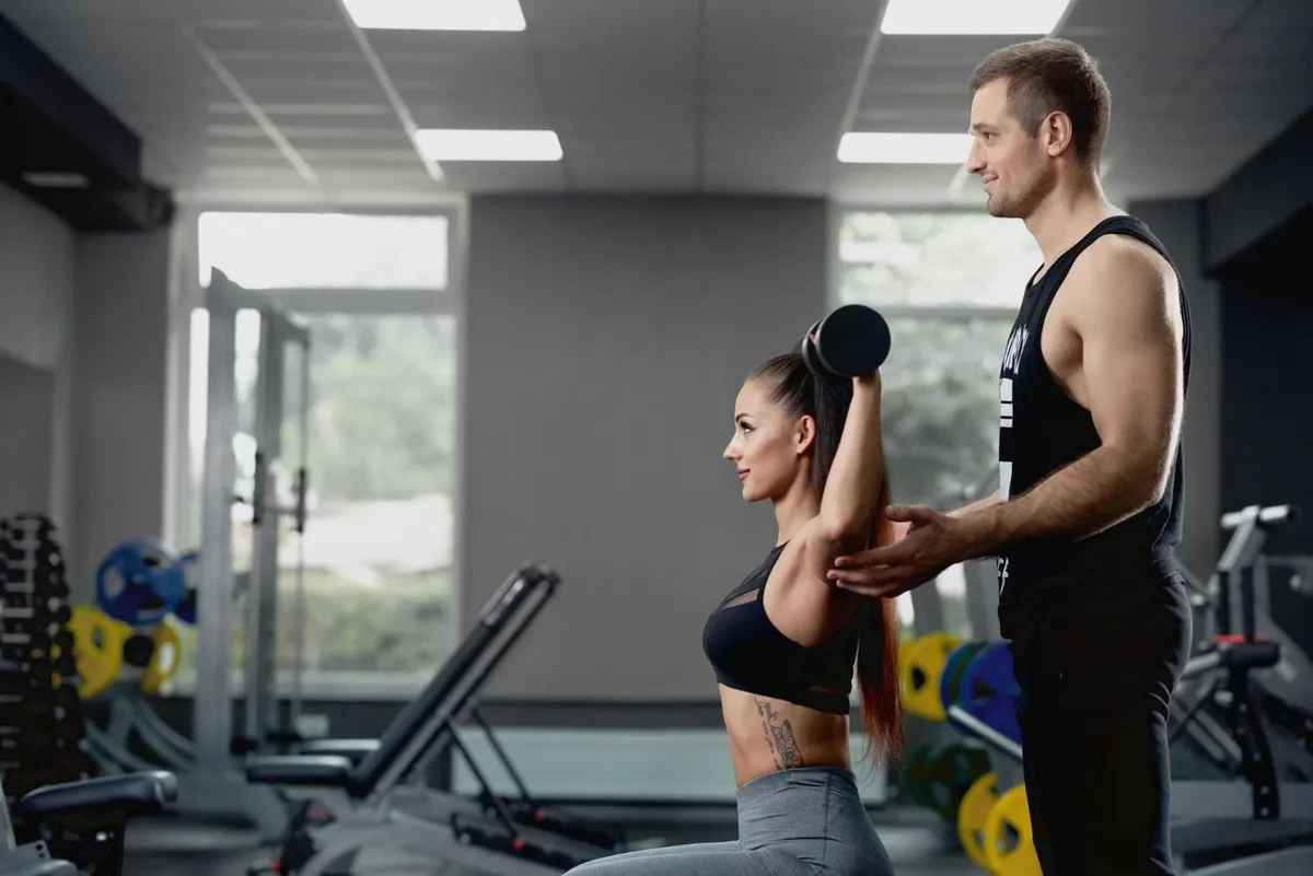 Personal trainer coaching a client through a workout in a gym